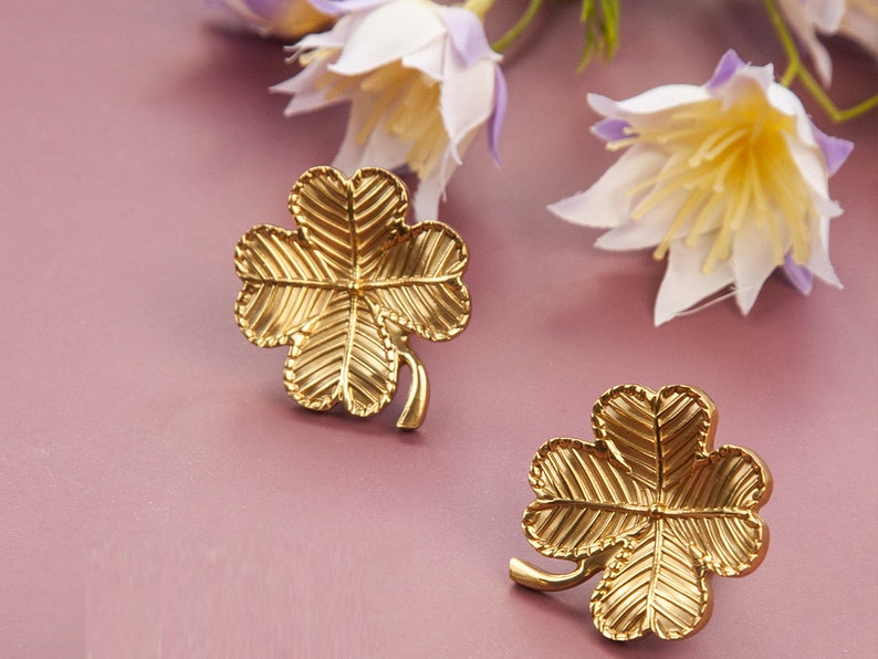 Peut inclure: Une paire de boucles d'oreilles en forme de tr&egrave;fle &agrave; quatre feuilles dor&eacute;es. Les boucles d'oreilles sont en m&eacute;tal et pr&eacute;sentent un design d&eacute;taill&eacute;.