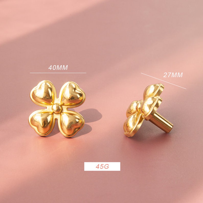 May include: Gold-toned metal cabinet knob with a four-leaf clover design. The knob measures 40 mm in diameter and 27 mm in height. It weighs 45 grams.