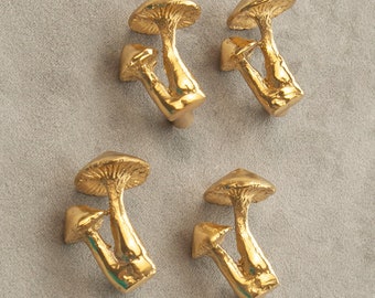 May include: Four gold mushroom-shaped drawer pulls. Each pull features two mushrooms, one on top of the other.