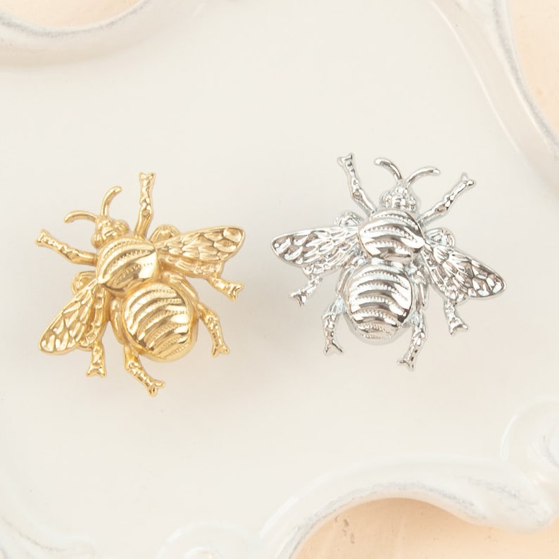 Peut inclure: Deux broches en forme d'abeille, l'une dor&eacute;e et l'autre argent&eacute;e, avec des ailes d&eacute;taill&eacute;es et un corps textur&eacute;.