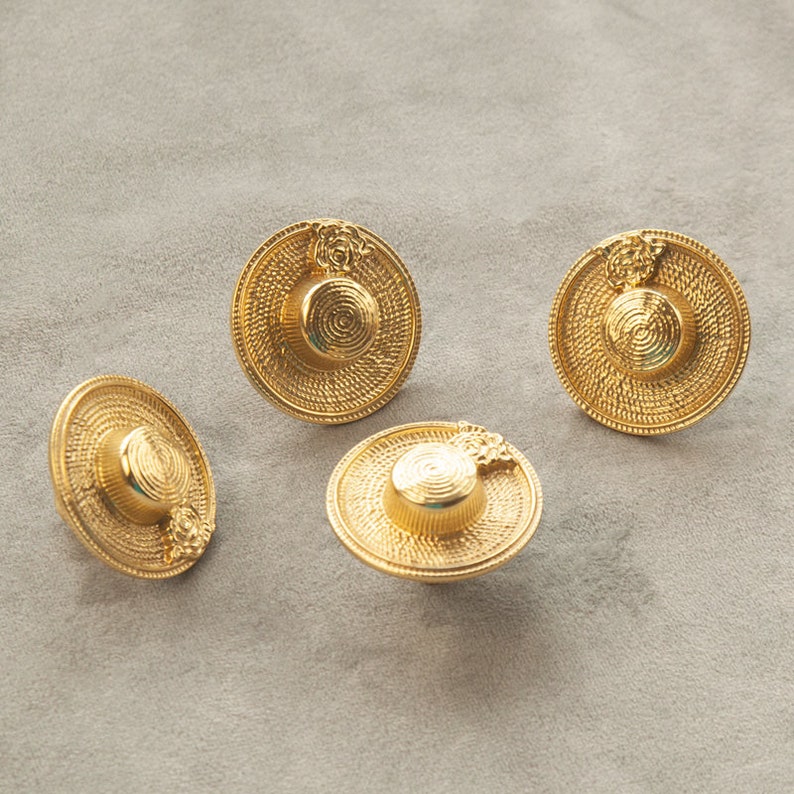May include: Four gold-coloured metal buttons shaped like miniature straw hats with a floral design.