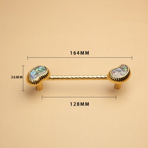 May include: Gold cabinet hardware with a twisted bar and iridescent shell accents. The hardware measures 164mm long and 128mm wide.