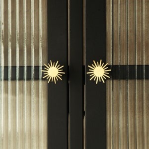 May include: Close-up of a black cabinet with two gold starburst-shaped door knobs.