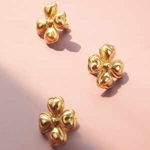 May include: Three gold-colored metal flower-shaped drawer pulls. Each pull has five petals and a raised center.