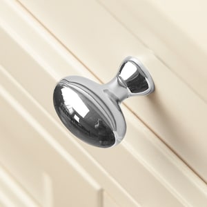 Op de afbeelding: Een gepolijste chromen kastknop met een ovale vorm en een ronde knop aan de bovenkant.
