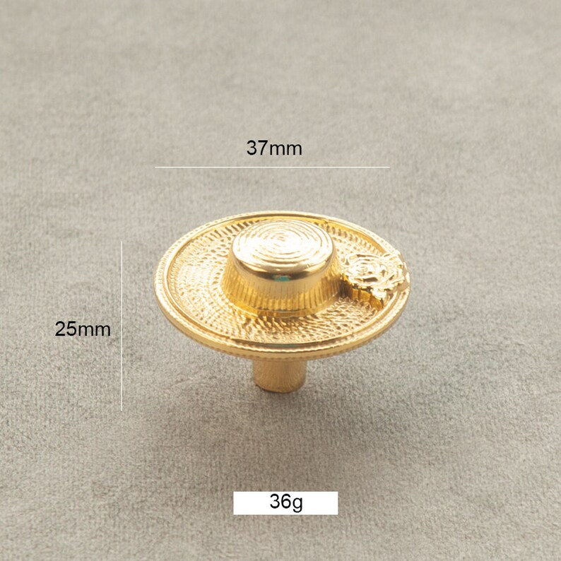 May include: Gold-toned metal cabinet knob shaped like a straw hat with a 37mm diameter and 25mm height. The knob weighs 36 grams.