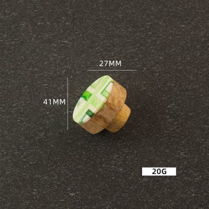 K&ouml;nnte beinhalten: Gr&uuml;ner und wei&szlig;er, gemusterter Holz-Knopf mit einem Durchmesser von 27 mm und einer H&ouml;he von 41 mm. Der Knopf wiegt 20 Gramm.