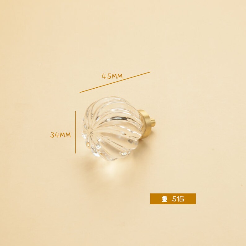 May include: Clear glass cabinet knob with a ribbed design and a gold metal base. The knob measures 4.5 cm in diameter and 3.4 cm in height. The weight of the knob is 51 grams.
