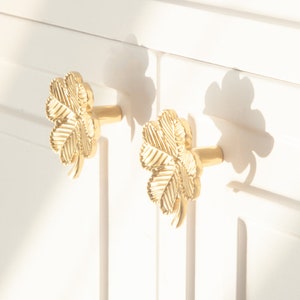 Peut inclure: Deux boutons de porte en forme de tr&egrave;fle en or avec un motif de feuille d&eacute;taill&eacute;.