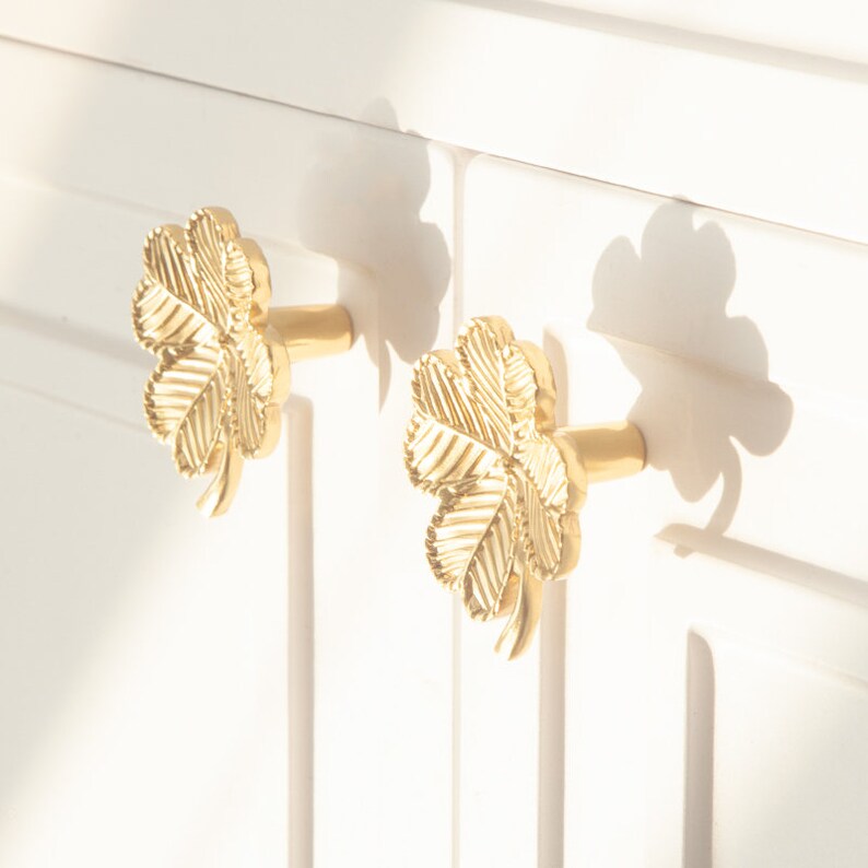 Peut inclure: Deux boutons de porte en forme de tr&egrave;fle en or avec un motif de feuille d&eacute;taill&eacute;.