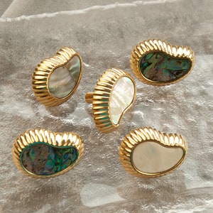 May include: Five gold-toned cabinet knobs with a scalloped edge and a mother-of-pearl inlay. The inlays are either white or iridescent green and blue.