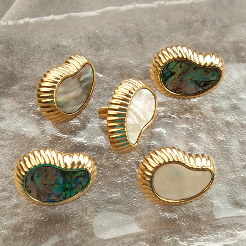 May include: Five gold-toned cabinet knobs with a scalloped edge and a mother-of-pearl inlay. The inlays are either white or iridescent green and blue.
