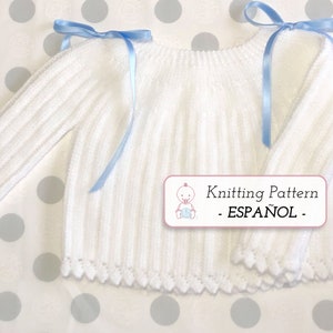 May include: White knitted baby sweater with blue ribbon ties. The sweater has a scalloped hem and ribbed texture. The image includes the text "Knitting Pattern - ESPAÑOL - "