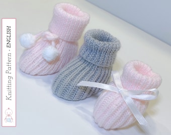 Op de afbeelding: Drie paar gebreide babyschoentjes. Eén paar is roze met witte pompoentjes, een ander paar is grijs en het derde paar is roze met een wit lint.