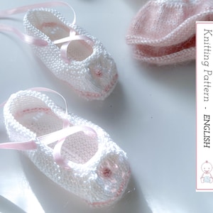 May include: Two white knitted baby booties with pink ribbon ties and accents. The booties are displayed on a white surface. The image also includes a pink knitted sock and a vertical sign that reads "Knitting Pattern - ENGLISH".