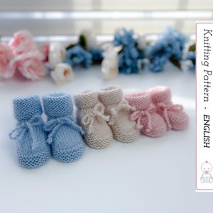 Puede incluir: Una colección de patucos de bebé tejidos en azul claro, beige y rosa. Cada par presenta un puño enrollado y un lazo delicado. La imagen incluye el texto "Knitting Pattern - ENGLISH".