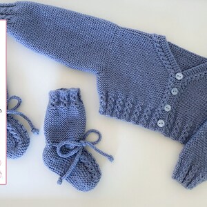 Puede incluir: Un conjunto de cardigan y botines de punto para bebé en color azul claro. El cardigan tiene cierre de botón y un patrón de punto decorativo. Los botines tienen cierre de lazo.