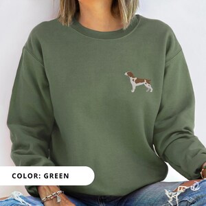 May include: A green sweatshirt with a brown and white dog illustration on the front. The text "COLOR: GREEN" is printed below the image.