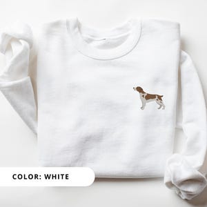 May include: White sweatshirt with a brown and white dog silhouette embroidered on the front. The text "COLOR: WHITE" is printed below the image.