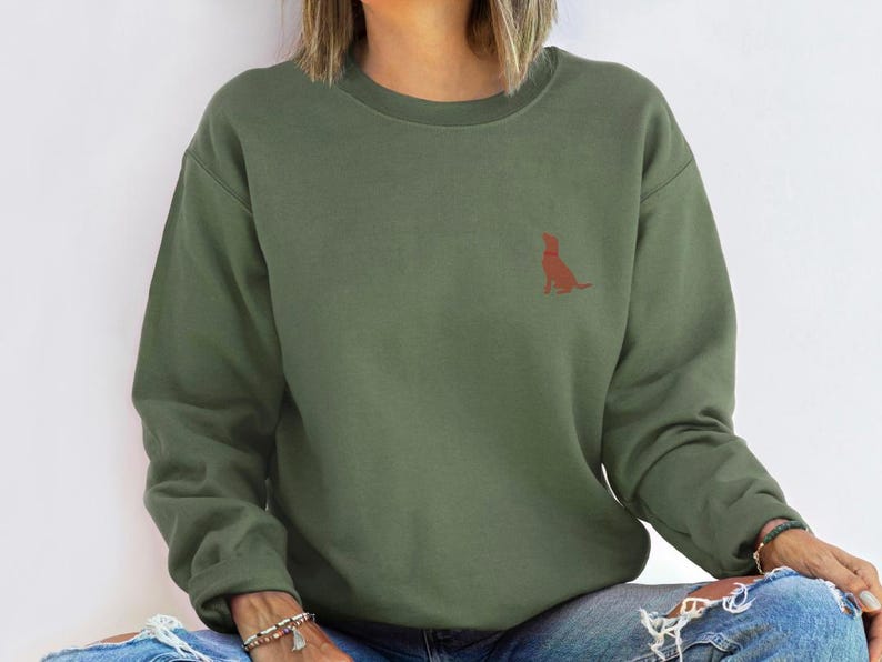 May include: A green sweatshirt with a small, red silhouette of a dog sitting on the left chest.