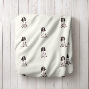 Può includere: Un tessuto bianco con un motivo ripetuto di cani Springer Spaniel neri e bianchi. I cani sono seduti e guardano in avanti.