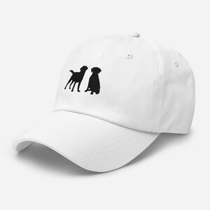 May include: White baseball cap with black embroidered silhouettes of two dogs. One dog is standing and the other is sitting.