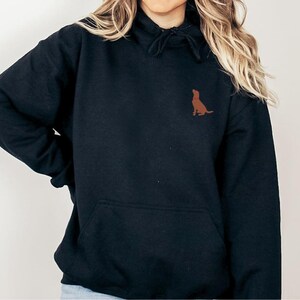 May include: Black hooded sweatshirt with a brown silhouette of a dog on the front.