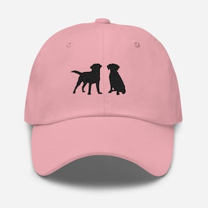 May include: A pink baseball cap with black embroidered silhouettes of two Labrador Retrievers facing each other.