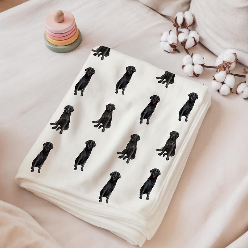 May include: White fleece blanket with a repeating pattern of black Labrador Retriever dogs. The dogs are all sitting and facing forward.