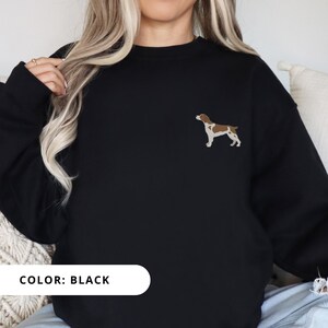 May include: Black sweatshirt with a brown and white dog silhouette embroidered on the left chest. The text "COLOR: BLACK" is displayed below the image.