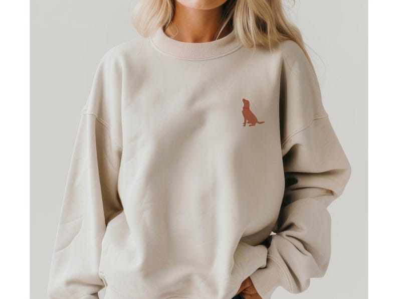 May include: A beige sweatshirt with a small, red embroidered dog silhouette on the front.