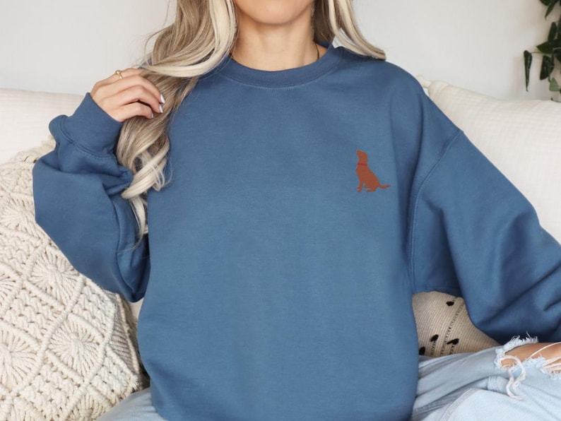 May include: A blue sweatshirt with a brown dog silhouette embroidered on the left chest.
