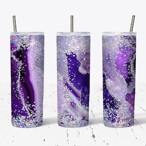 Könnte beinhalten: Drei Edelstahlbecher mit Deckel und Strohhalmen. Jeder Becher hat ein Design aus violettem und silbernem Achat mit Glitzerakzenten.