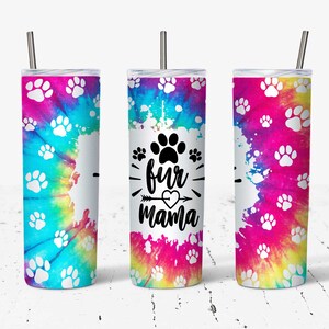 May include: Three stainless steel tumblers with a tie-dye pattern and white paw prints. The centre tumbler has the text "fur mama" with a heart and arrow.