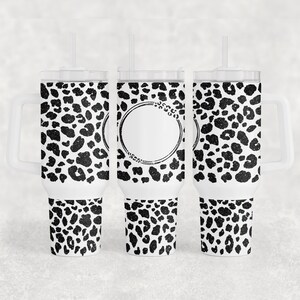 May include: Three white stainless steel tumblers with black leopard print designs. The centre tumbler has a blank circle in the design.