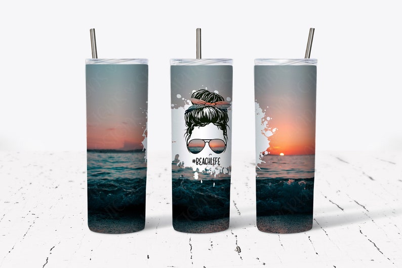 May include: Three stainless steel tumblers featuring a sunset and ocean scene. The centre tumbler has a woman with a messy bun and sunglasses with the text "Beachlife".
