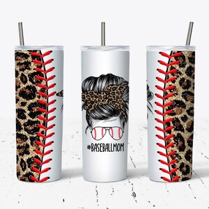 Pode incluir: Três copos de aço inoxidável com tema de beisebol. Os copos apresentam um design de estampa de leopardo e costuras de beisebol vermelhas. O copo do meio tem um gráfico de uma mulher com um coque bagunçado e óculos de sol. O texto "#BASEBALLMOM" está impresso no copo do meio.