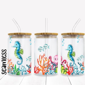 May include: Three clear glass tumblers with bamboo lids and straws. Each tumbler features a different underwater scene with a seahorse, coral, and fish. The first tumbler has a blue and green seahorse, the second has a pink octopus, and the third has a blue and green seahorse.