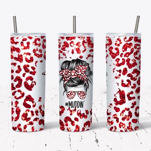 May include: A white tumbler with a red glitter leopard print design. The tumbler features a black and white illustration of a woman with a messy bun and a leopard print headband. The text "#MUDDIN'" is printed below the illustration.