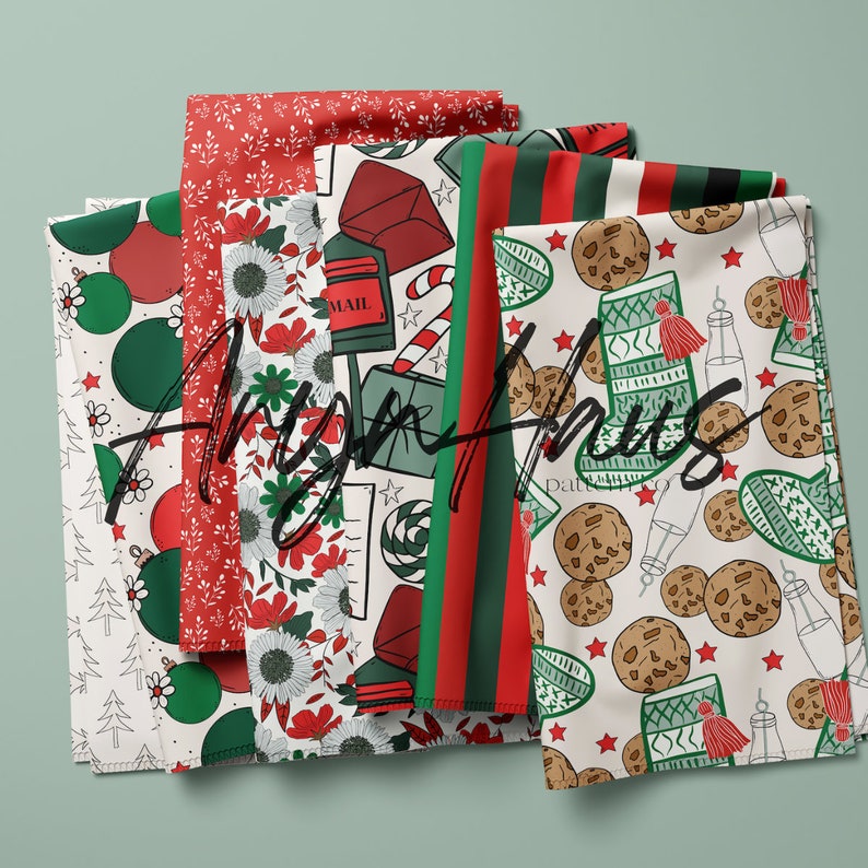 May include: Several folded fabrics featuring festive Christmas patterns. Designs include baubles, floral arrangements, post boxes, candy canes, cookies, and striped patterns in red, green, and white. The text "Angie Hughes" is visible across the fabrics.
