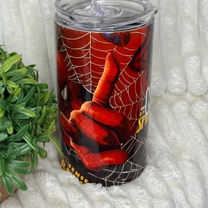 May include: A stainless steel tumbler with a Spider-Man design. The tumbler displays a close-up of Spider-Man's hand and web, with the words "Spider Sense" visible. It includes a clear lid.