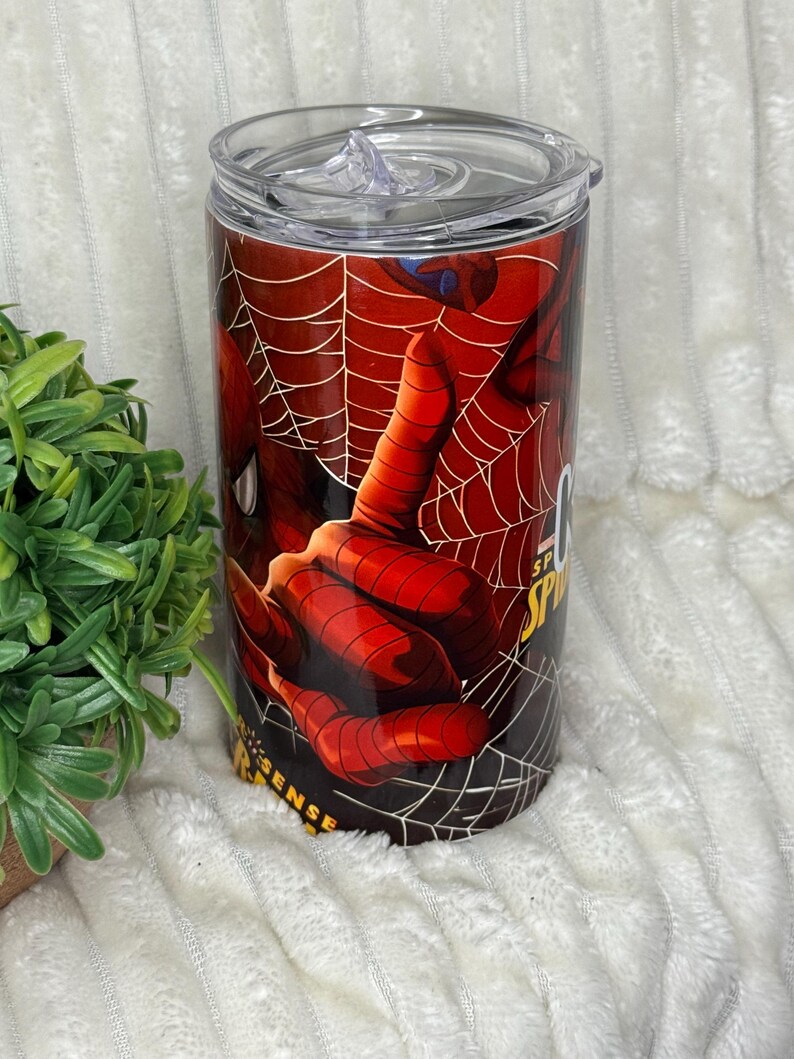 May include: A stainless steel tumbler with a Spider-Man design. The tumbler displays a close-up of Spider-Man's hand and web, with the words "Spider Sense" visible. It includes a clear lid.
