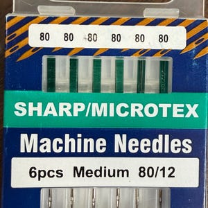 May include: A package of Klasse' brand machine needles. The package is blue with a white label that reads "Machine Needles" and "6pcs Medium 80/12". The top of the package has the numbers "80" repeated six times.