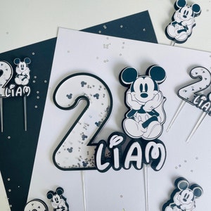 Puede incluir: Conjunto de adornos para tartas en blanco y negro con Mickey Mouse, el n&uacute;mero 2 y el nombre Liam. El n&uacute;mero 2 est&aacute; decorado con purpurina plateada.