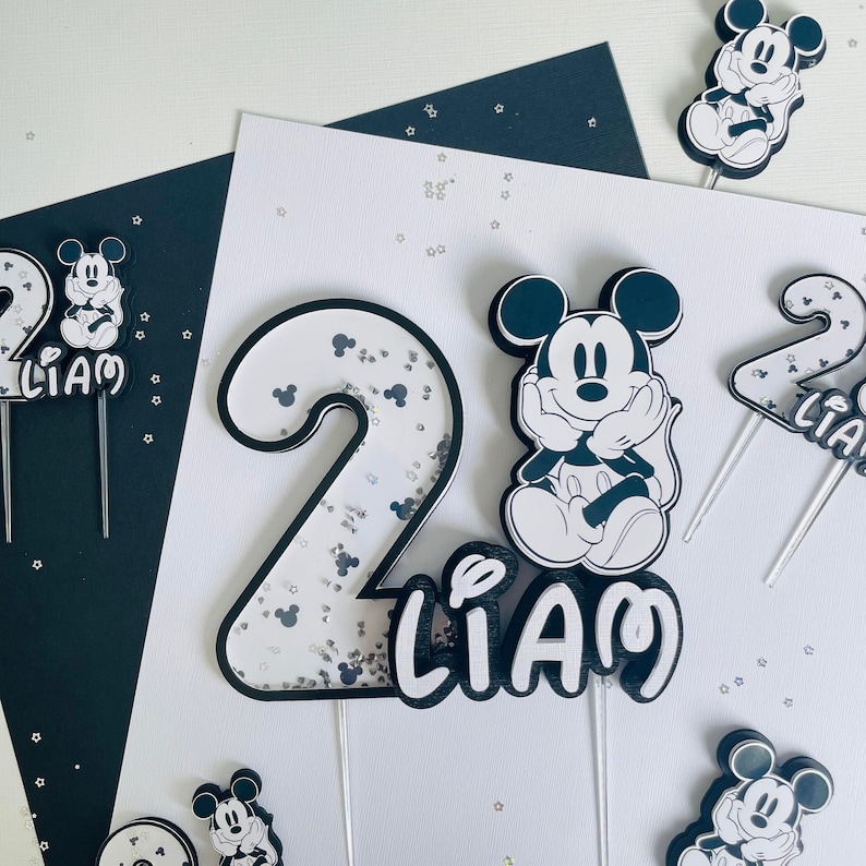 Puede incluir: Conjunto de adornos para tartas en blanco y negro con Mickey Mouse, el n&uacute;mero 2 y el nombre Liam. El n&uacute;mero 2 est&aacute; decorado con purpurina plateada.
