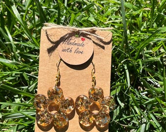 Brincos artesanais em resina com flocos de ouro em formato de flor.