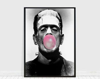 Pode incluir: Uma fotografia a preto e branco de Frankenstein a soprar uma grande bolha rosa. A imagem está enquadrada numa moldura preta.