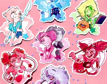 May include: Six colorful cartoon stickers featuring characters from the animated television series Steven Universe. The stickers are on a pink background with blue glitter. The characters are: Lapis Lazuli, Peridot, Pink Pearl, Spinel, Amethyst, and Pearl.