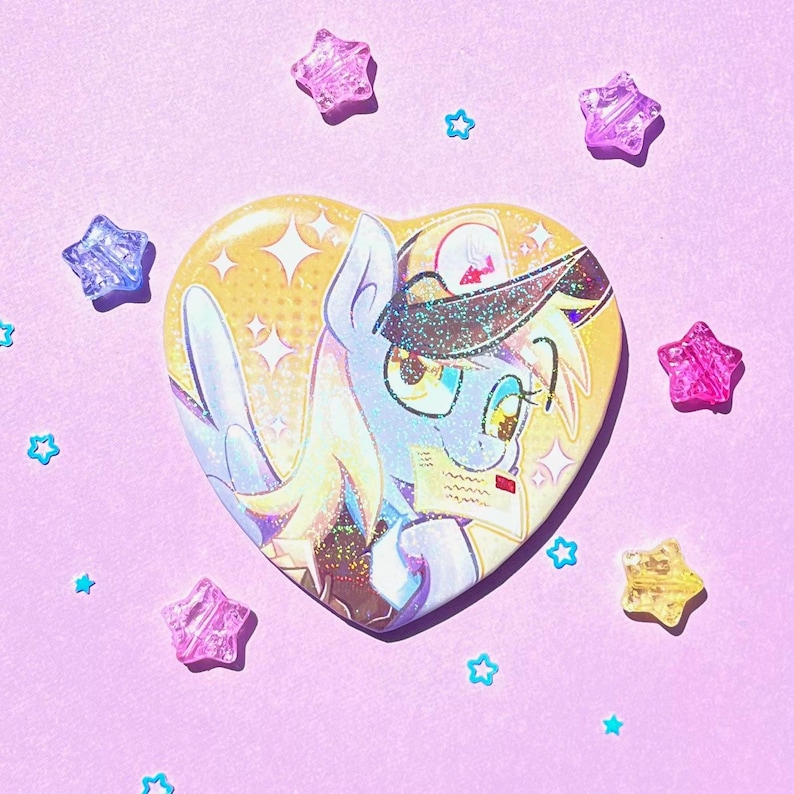 May include: A heart-shaped button featuring a cartoon pony with a yellow and blue color scheme. The pony has a hat and glasses. The background is yellow with white stars. Surrounding the button are star-shaped and star-shaped confetti.
