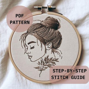 Pode incluir: Bastidor de bordado com um desenho detalhado do perfil de uma mulher com os olhos fechados e um coque. O desenho é bordado com linha marrom sobre tecido bege. O texto na imagem diz "PDF PATTERN" e "STEP-BY-STEP STITCH GUIDE".